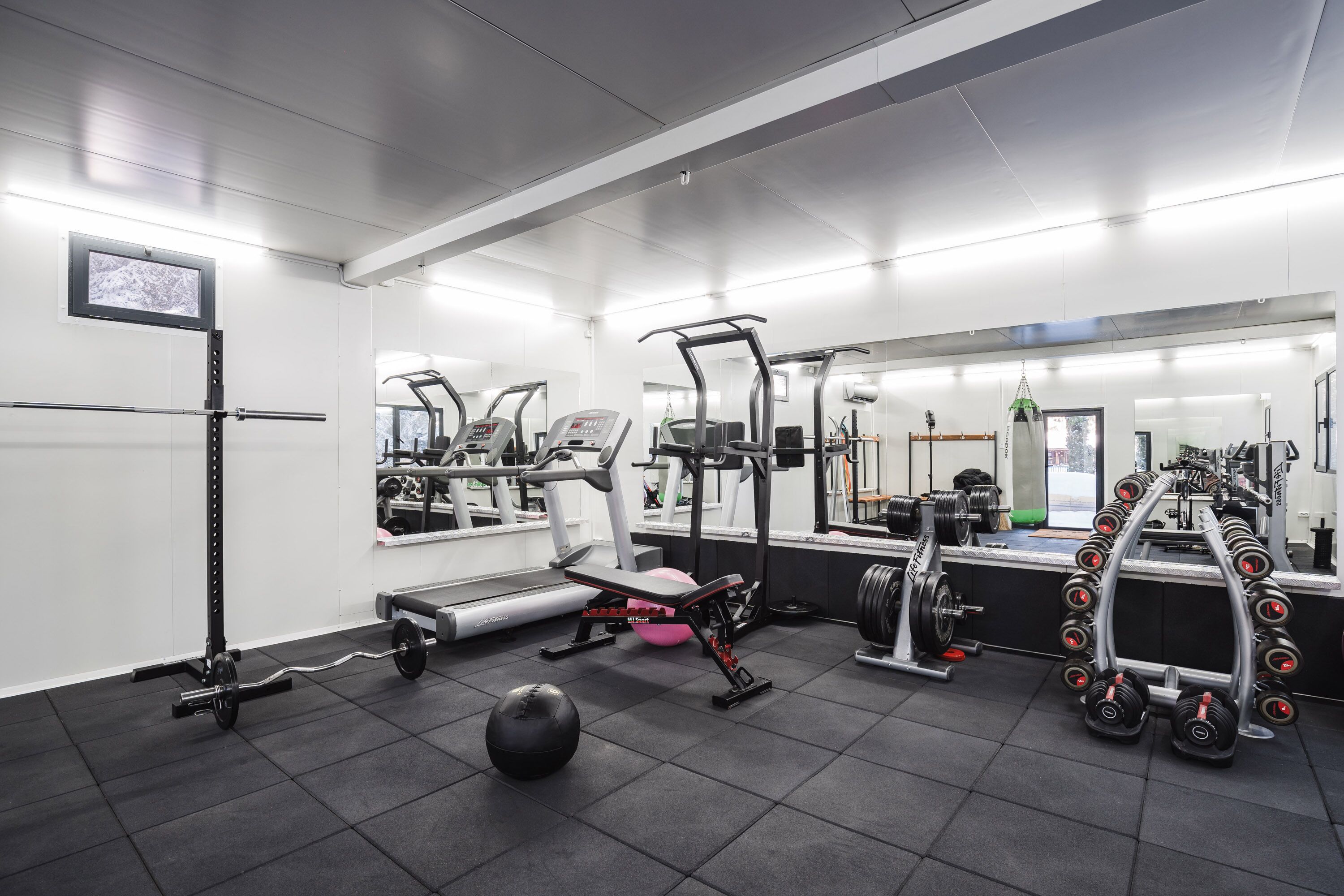 Une salle de sport équipée de matériel d’exercice, d’un tapis de course et d’un support à poids.