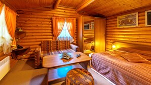 Une chambre de style rustique, avec un plafond en bois, un canapé, un lit, une table avec une télécommande et une lampe.