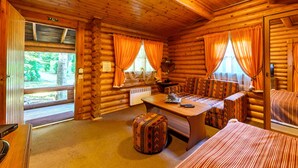 L’intérieur d’une cabane en rondins, avec une table à manger en bois, des bancs et un canapé.