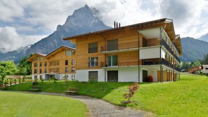 A multi-story wooden building with balconies, set against a mountainous backdrop. - Victoria Alpine Park (Kandersteg)