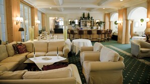 A spacious hotel lobby with multiple seating areas, a bar, and a dining setup. - Victoria Alpine Park (Kandersteg)