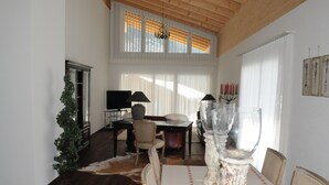 A dining area with a table set for two, a chandelier, and a menorah on the windowsill. - Victoria Alpine Park (Kandersteg)