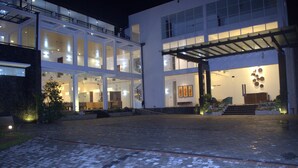 A modern building with a glass facade, a covered entrance, and a well-lit interior. - Ripon Grand Hill (Nuwara Eliya)