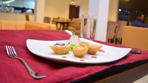 A dining table with a white plate of appetizers, a fork, and a glass of water. - Ripon Grand Hill (Nuwara Eliya)