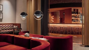 A modern bar area with red seating, wooden accents, and a well-lit interior. - Perianth Hotel, a member of Design Hotels (Athens)