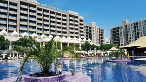 A hotel with multiple balconies, a swimming pool, and outdoor seating areas. - Sandapart Royal Beach Apartments (Sunny Beach)