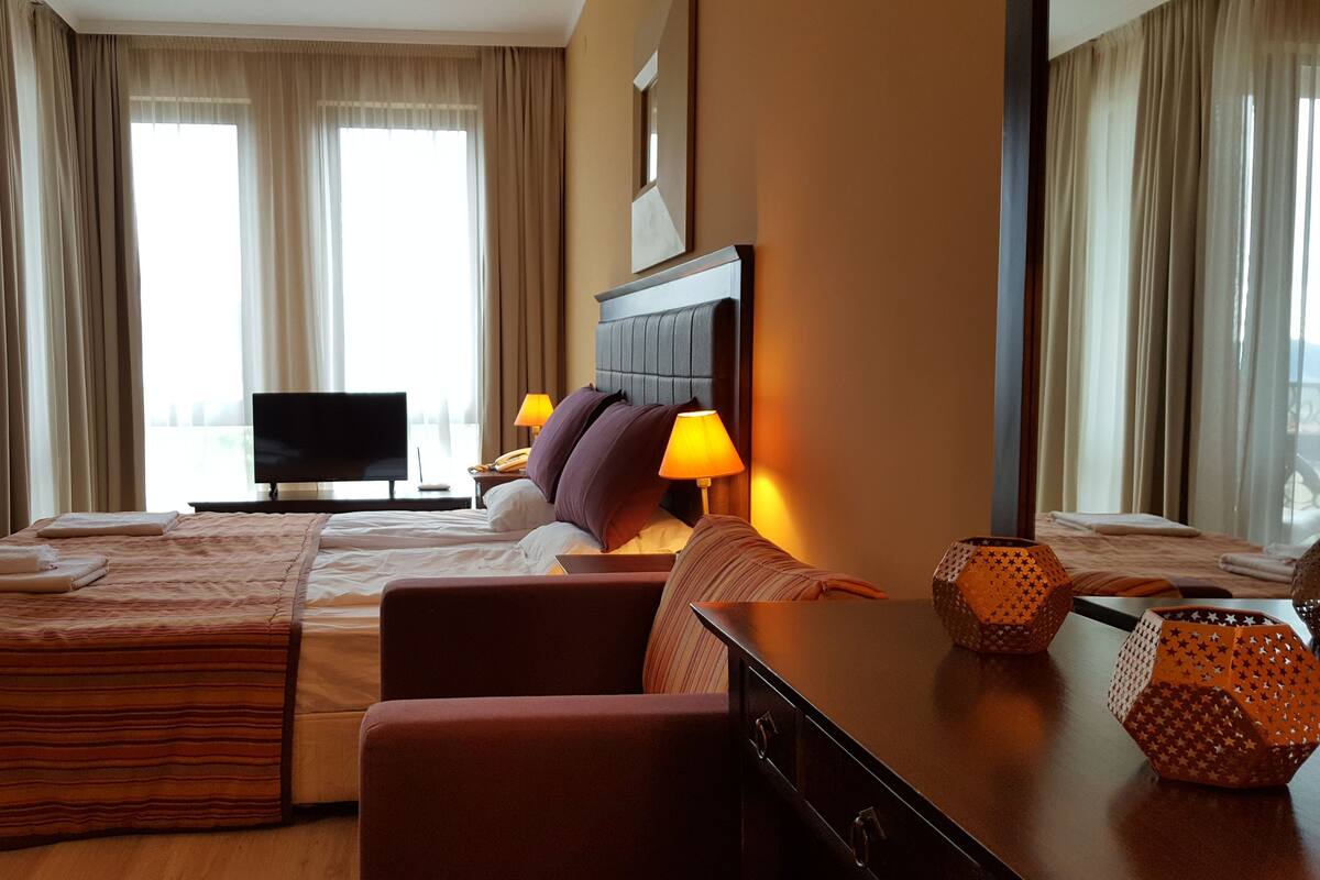 Una habitación de hotel con una cama grande, un escritorio, televisión y vistas a la ciudad.