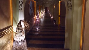 Un pasillo con una escalera, paneles decorativos en la pared y lámparas colgantes.