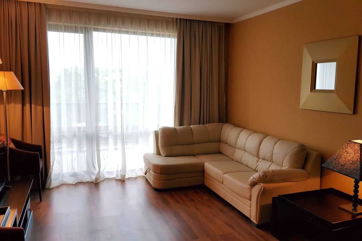 Una sala de estar moderna con un sofá modular, un televisor de pantalla plana y una lámpara.