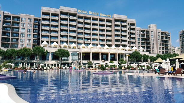 Un hotel con varios balcones, piscina y sombrillas de exterior.