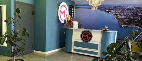 A reception area with a desk, a chandelier, and a cityscape mural on the wall.
