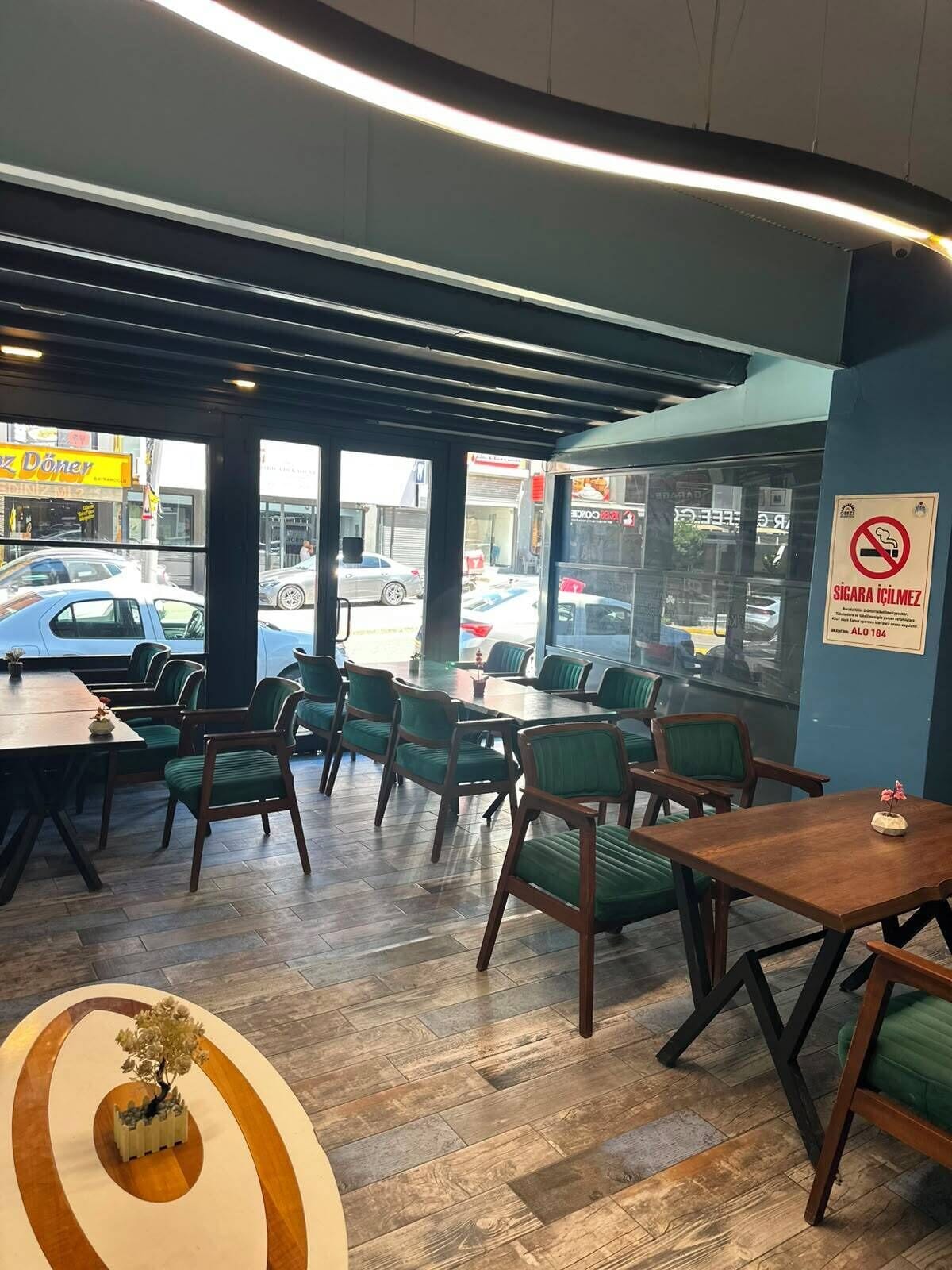 An indoor seating area with tables and chairs, a view of the street outside, and a no-smoking sign on the wall.