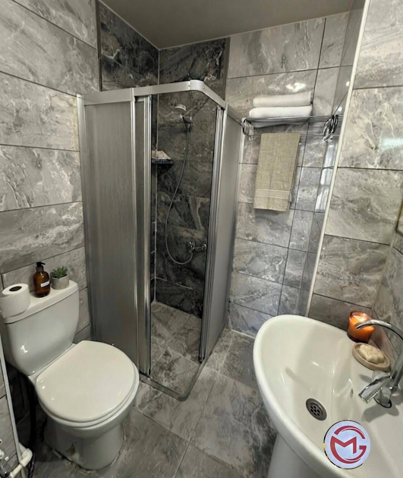 A bathroom with a toilet, shower, and sink.