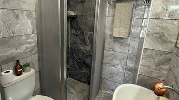 A bathroom with a toilet, shower, and sink.