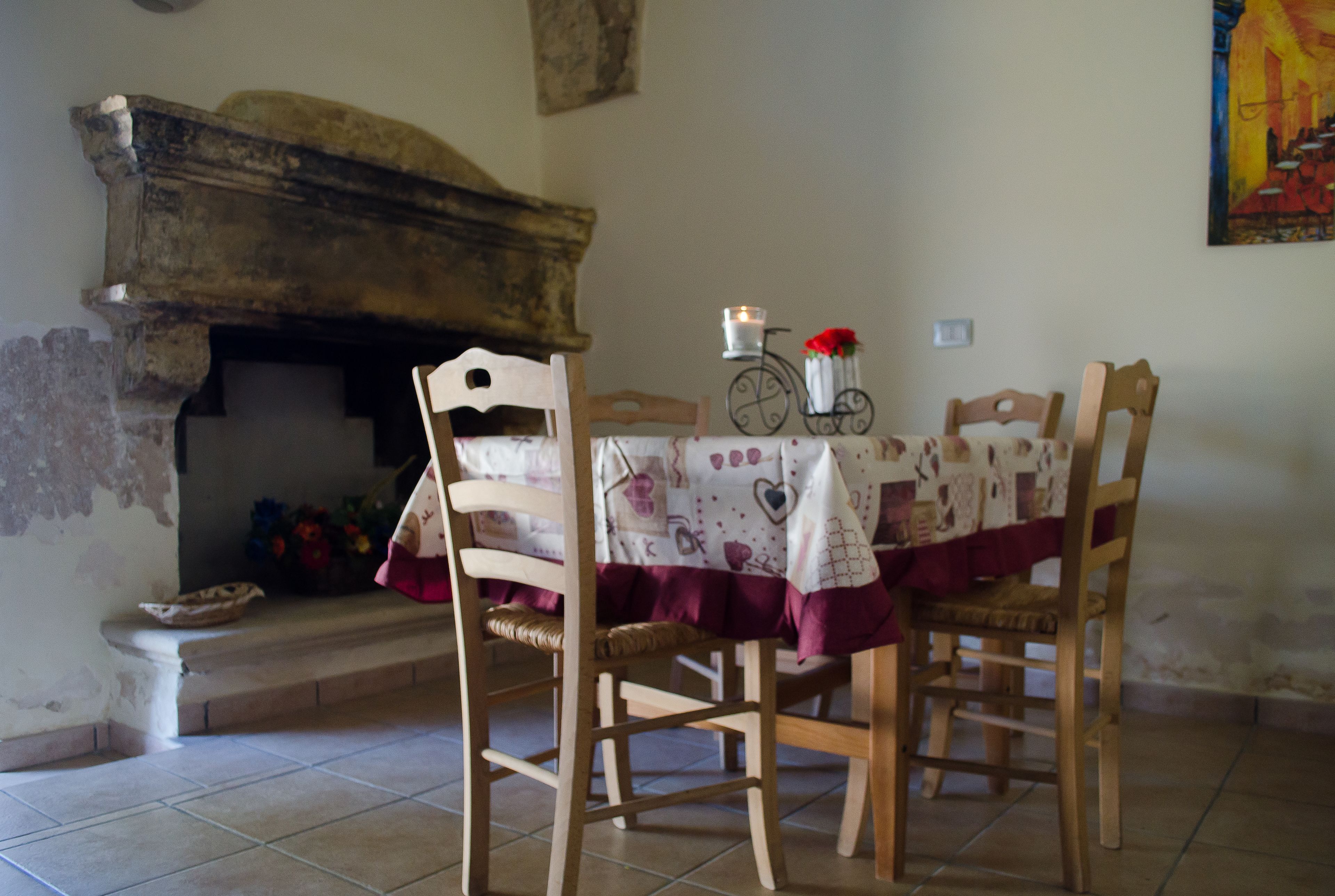 A dining area with a table set for two, a wooden chair, a small table with a candle, and a decorative bicycle.