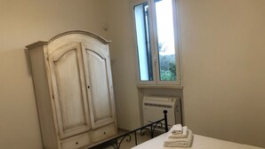 A bedroom with a bed, a wardrobe, a window, and an air conditioning unit. - Agriturismo Capani (Alezio)