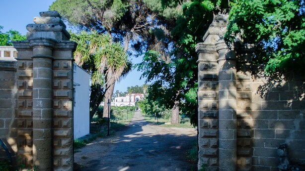 A paved pathway leading through stone gates with a building in the background. - Agriturismo Capani (Alezio)