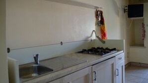 A kitchen with a sink, stove, and cabinets. - Agriturismo Capani (Alezio)