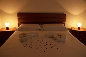 A hotel room with a large bed, two bedside tables, and a wooden headboard. - Agriturismo Capani (Alezio)