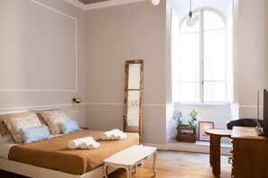A bedroom with a bed, a bedside table, a mirror, a window with shutters, and a desk with a chair. - Banco19B&B (Rome)