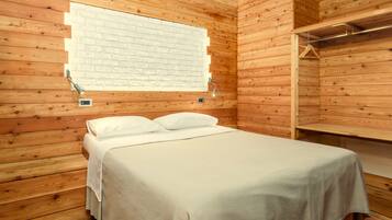 Een kamer met houten lambrisering, een bed, een kledingrek en een raam met een wit baksteenmotief.