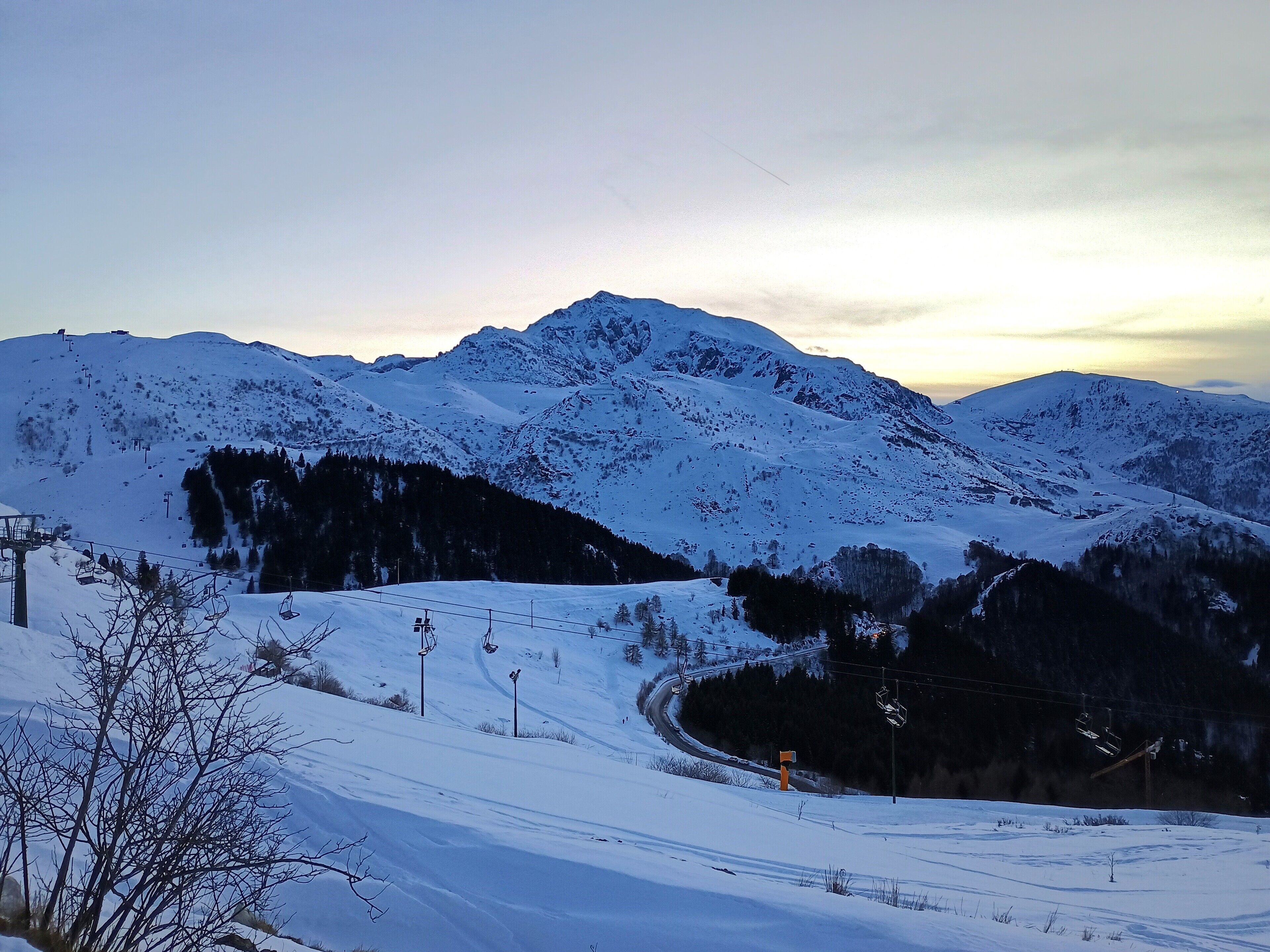 Un paysage de montagne enneigé, avec des remontées mécaniques et un ciel dégagé.