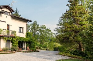 Una casa de dos pisos con camino de grava y un porche cubierto con mobiliario exterior.