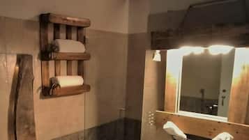 Ein Badezimmer mit einem hölzernen Regal mit Handtüchern, einem Spiegel mit Beleuchtung darüber und einem Waschbecken mit Handtuchhalter.