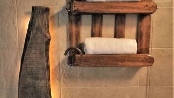A wooden towel rack with two towels hanging on it, mounted on a tiled wall.