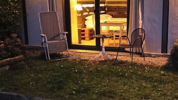 Una habitación de hotel con una puerta corrediza de vidrio que da a un comedor, una pequeña mesa y dos sillas.