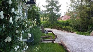 Un jardín con un sendero de grava, vallas de madera y una silla.