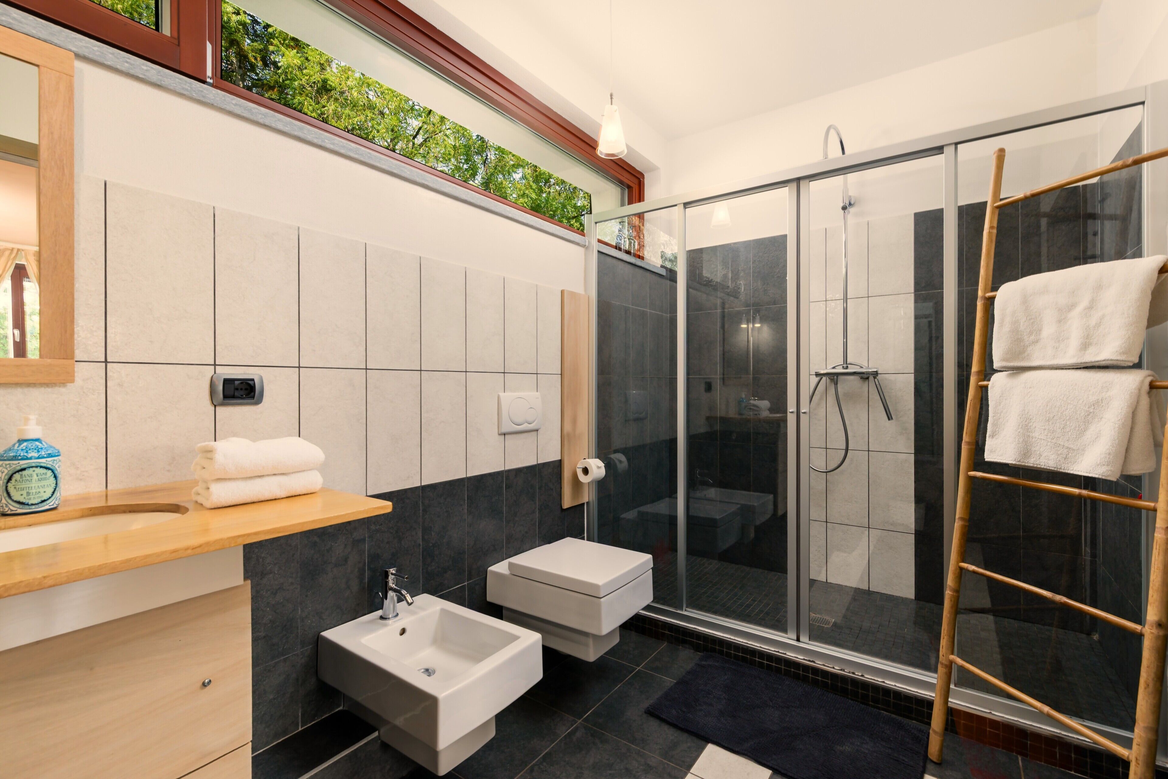 A modern bathroom with a glass shower enclosure, a sink, and a vanity with a mirror.