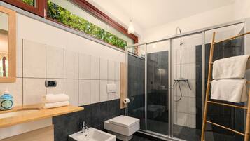 A modern bathroom with a glass shower enclosure, a sink, and a vanity with a mirror.