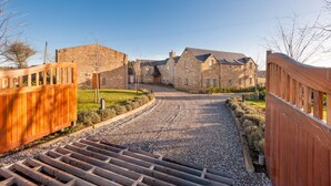 A gravel driveway leading to a stone building with a wooden fence on one side. - The Queens View Luxury B&B (Linlithgow)