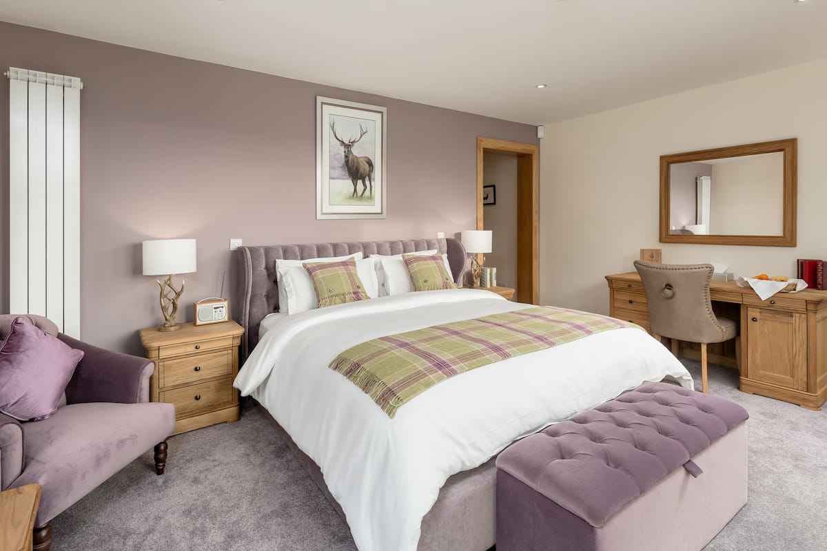 A bedroom with a large bed, a desk, a chair, and a nightstand.