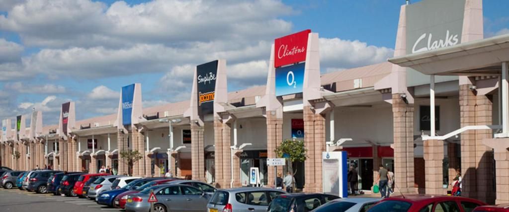 A row of commercial buildings with various business signs, including a Chevron gas station and a store named 'Clintons.'