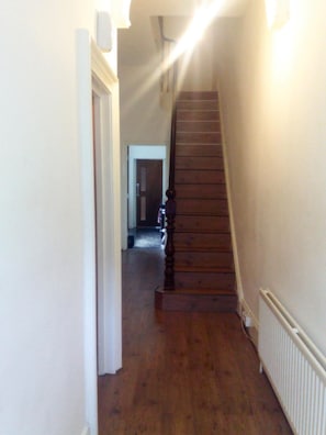 A wooden staircase in a hallway with a white radiator on the right. - Outram 26 (Stockton-on-Tees)