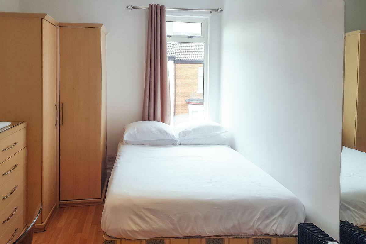 A bedroom with a bed, a wardrobe, and a window.