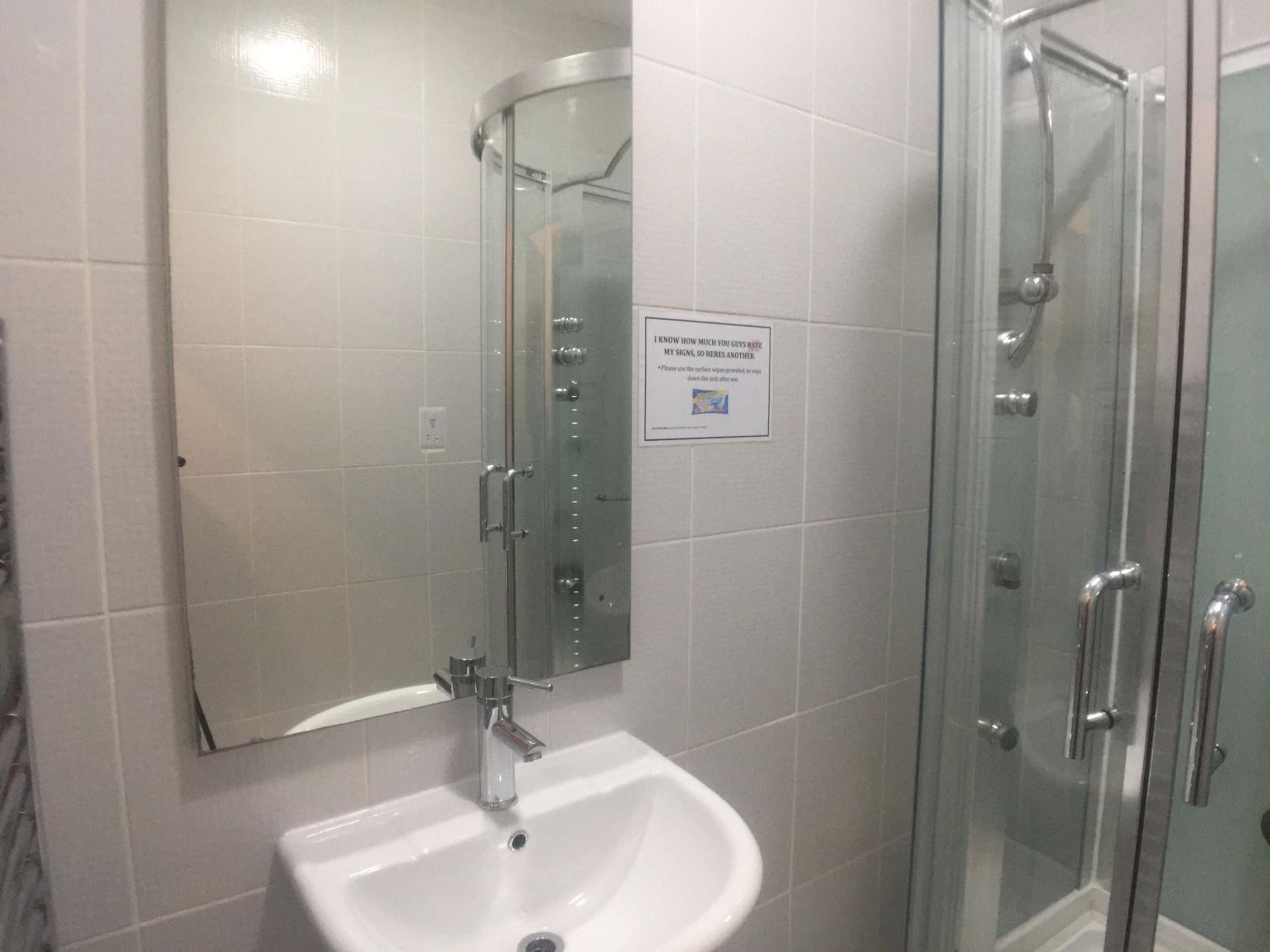 Un baño con un lavabo blanco, un espejo y una cabina de ducha de vidrio.