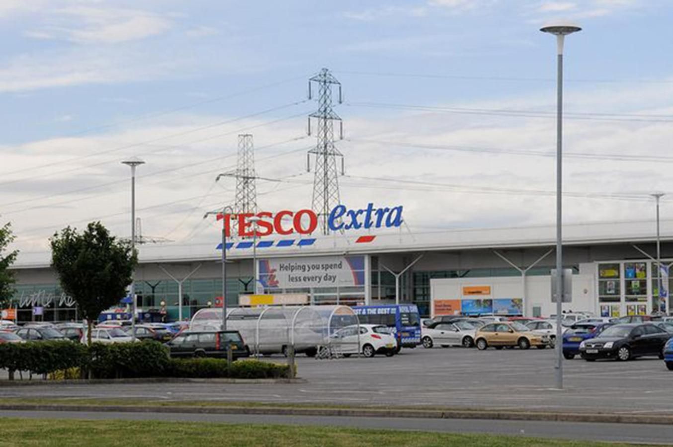 A Tesco Extra store with a parking lot and a large building structure.