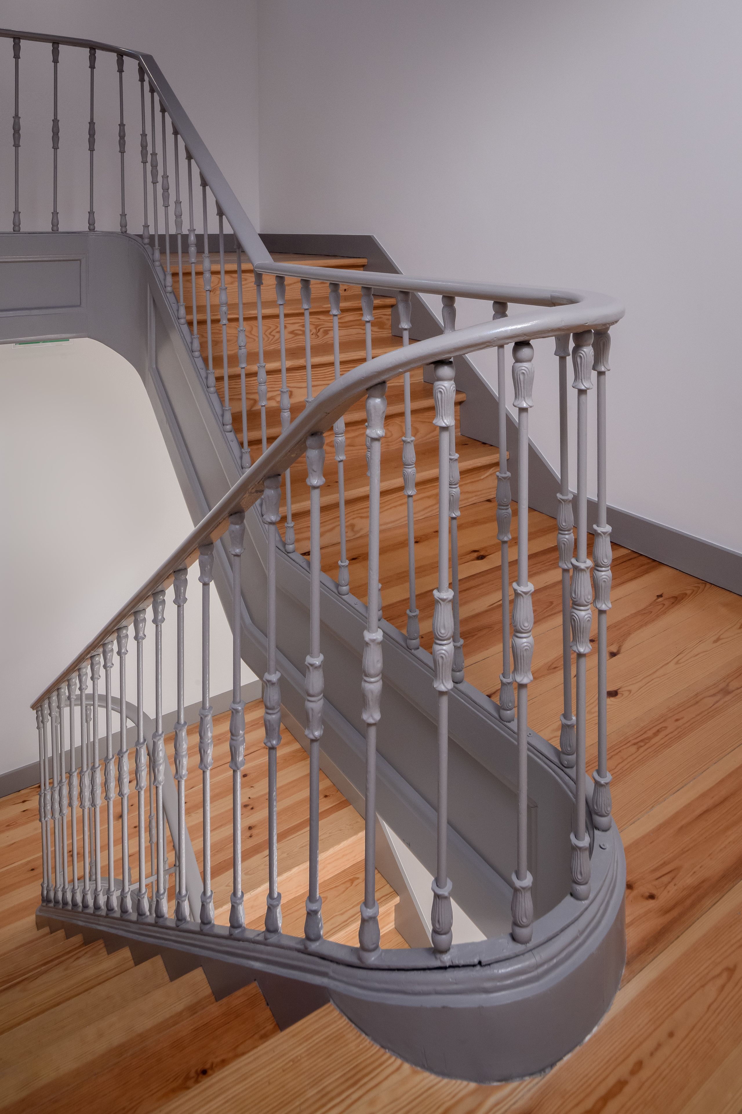 A staircase with a curved design, wooden steps, and a metal railing.