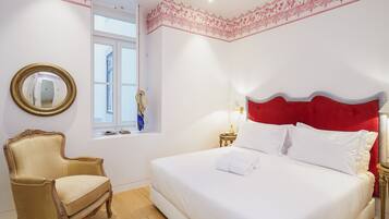 Een slaapkamer met een bed, een stoel, een raam en een spiegel.