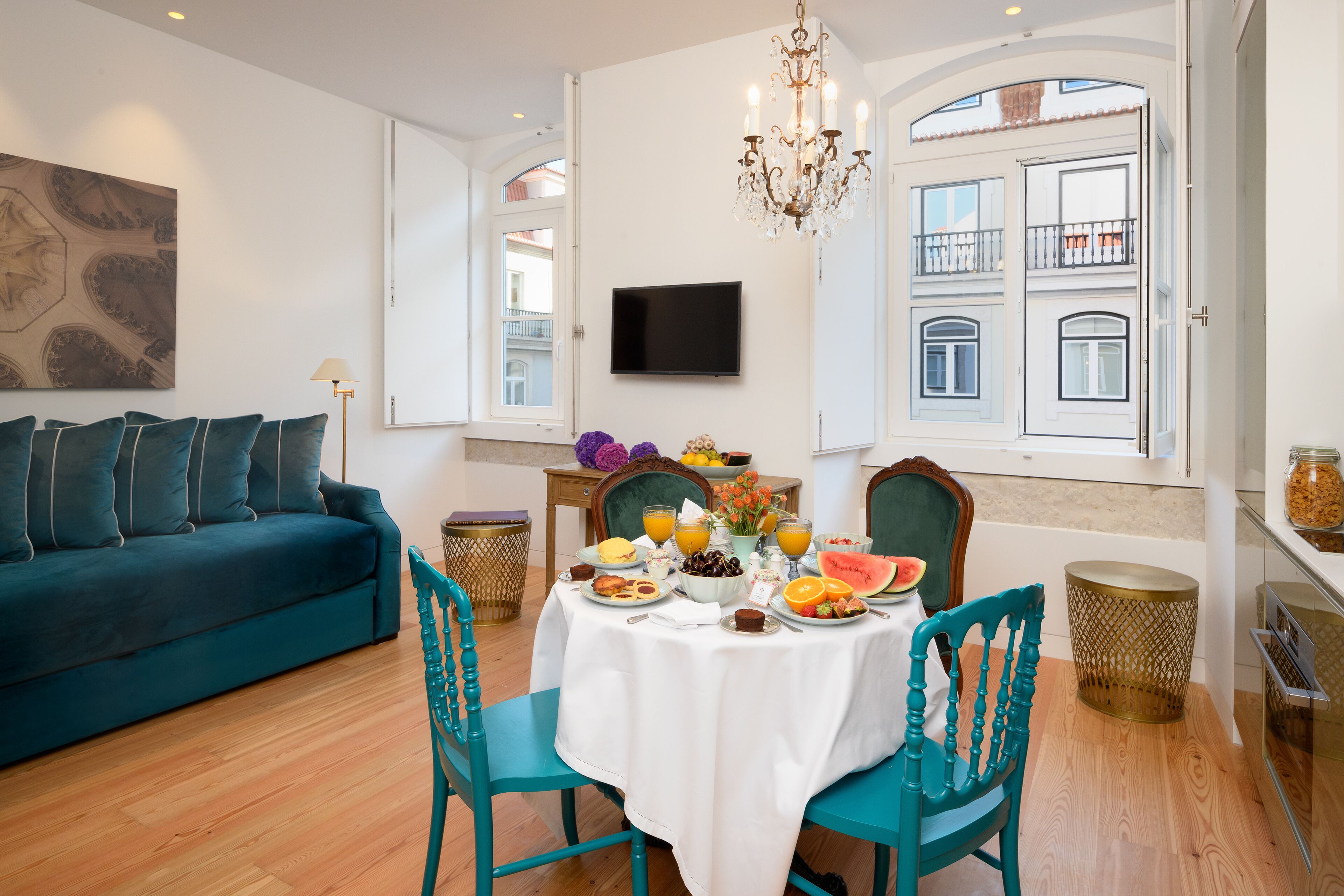 A dining area with a table set for breakfast, a sofa, and a TV mounted on the wall.