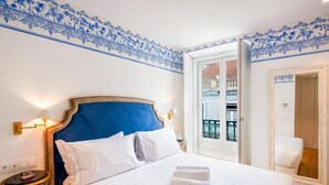 A hotel room with a large bed, white bedding, a blue headboard, and a decorative blue and white border on the walls. - Residentas Aurea (Lisbon)