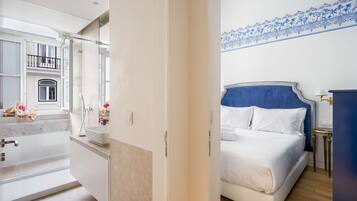 Quarto de hotel com cama, mesa de cabeceira, espelho e vista para uma varanda.