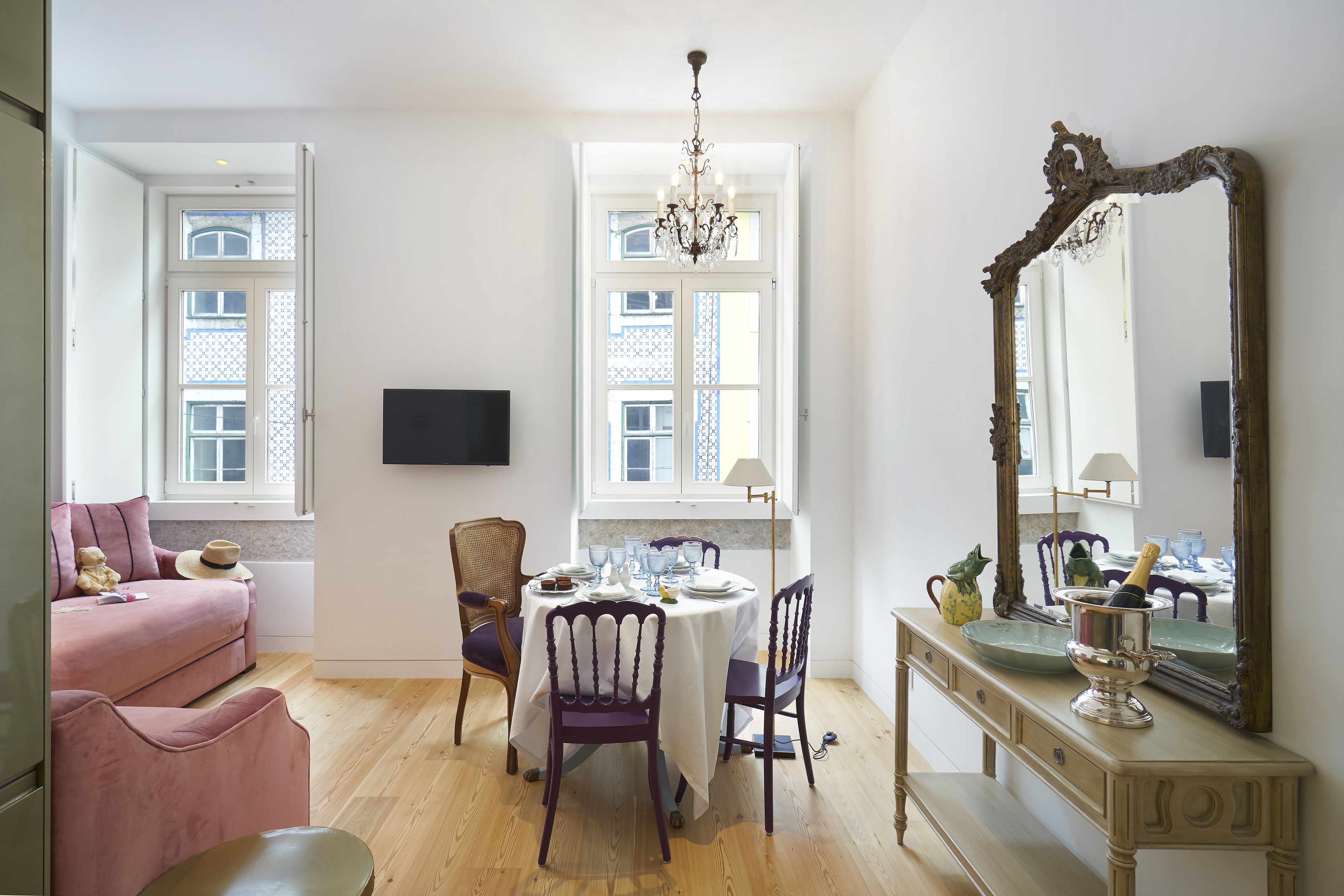 Un coin repas avec une table dressée pour quatre personnes, un canapé et un miroir au mur.