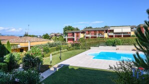 A residential area with a swimming pool, a well-maintained lawn, and a building with balconies. - Desenzanoloft – Butterfly and Pools (Desenzano del Garda)