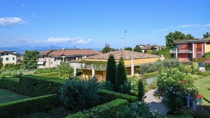 A residential area with houses, a yellow building with a red roof, and a clear blue sky. - Desenzanoloft – Butterfly and Pools (Desenzano del Garda)