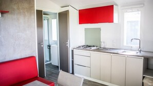 Een moderne keuken met een rode bovenkast, een gasfornuis en een spoelbak.