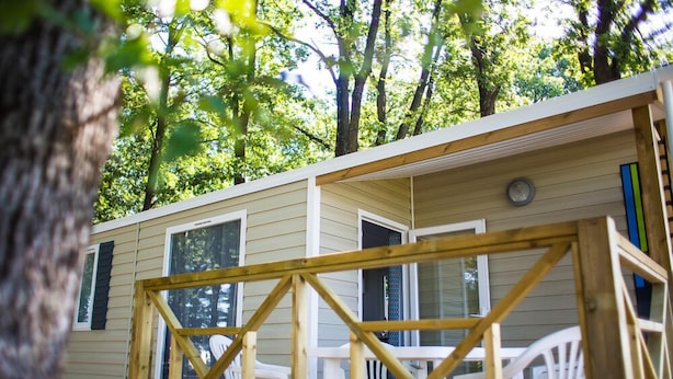 Een houten chalet met terras, omringd door bomen.
